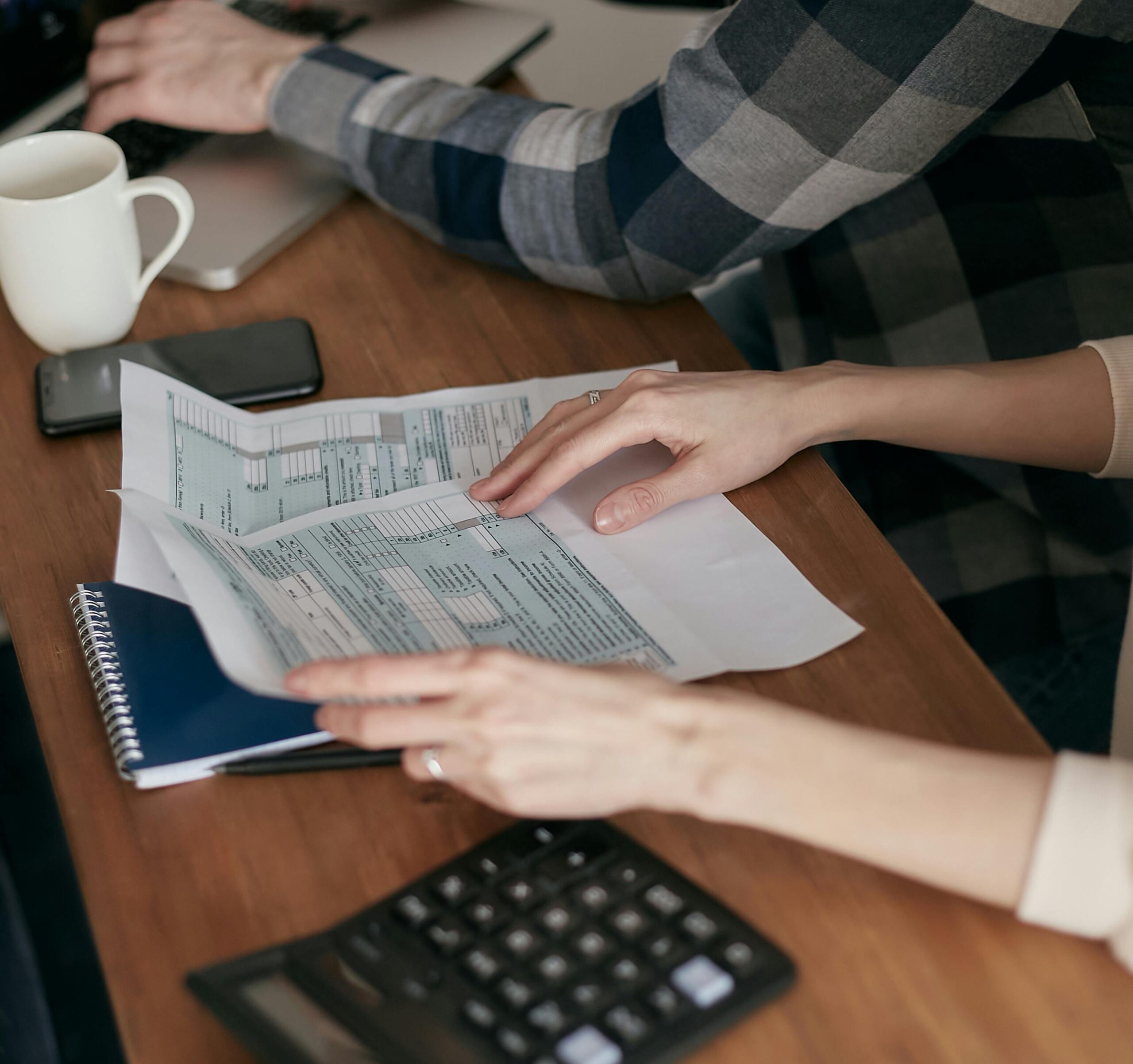 Documents MaPrimeRénov’ 2026 étalés sur une table avec calculatrice, ordinateur portable et mains triant les justificatifs